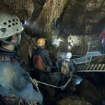 Groupe en accrogrotte : casque et lampe frontale, guide près d’une passerelle.